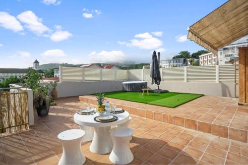 a patio with a white table and chairs on a roof at Appartement Bourg de Schoelcher - Rooftop in Schœlcher