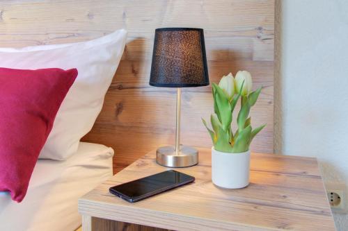 a table with a lamp and a plant on a bed at Apartment Landhotel Zum Storchennest in Bann