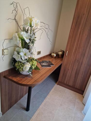 a vase of white flowers on a wooden desk at Résidence Aston la Scala in Nice