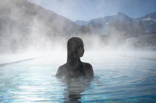 a man in the water in a hot tub at Österreichischer Hof-im Bademantel direkt in die Alpentherme in Bad Hofgastein