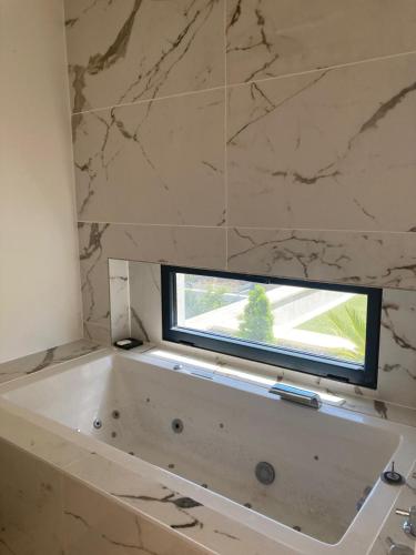 La salle de bains est pourvue d'une baignoire blanche et d'une fenêtre. dans l'établissement Maison avec piscine, à Bruges