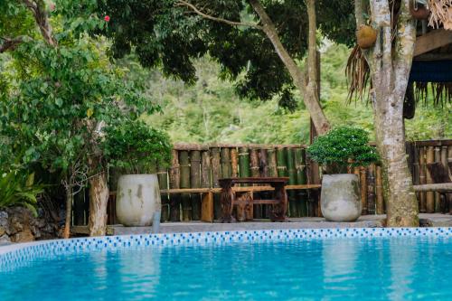 a swimming pool with a table and some trees at Ha Giang Xanh Retreat - Trekking, Tour, Motorbike Rental in Ha Giang