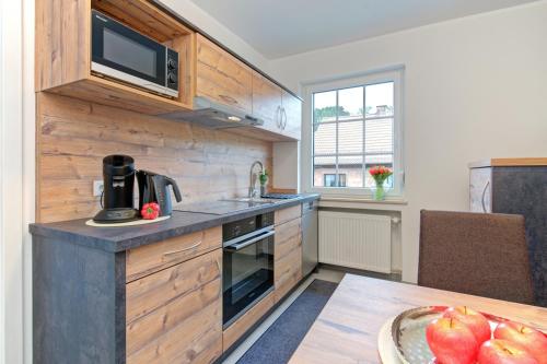 a kitchen with wooden cabinets and a table with a bowl of apples at Apartment Landhotel Zum Storchennest in Bann