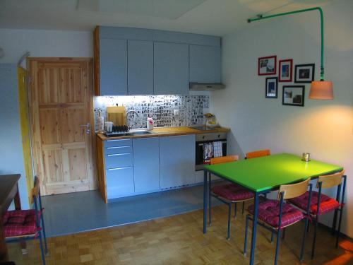 eine Küche mit einem grünen Tisch und einigen Stühlen in der Unterkunft Bad Chaka Apartment in Bovec