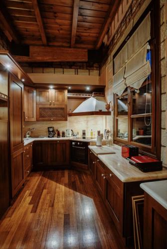 a large kitchen with wooden cabinets and wooden floors at PanThea Stone Villa in Aígio