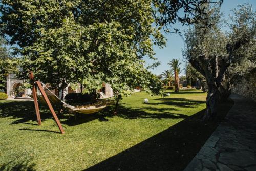 a hammock in the grass next to a tree at PanThea Stone Villa in Aígio