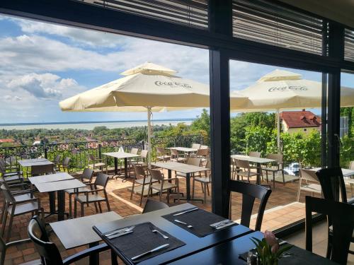 a restaurant with tables and chairs and umbrellas at Zenit Wellness Hotel Balaton in Vonyarcvashegy
