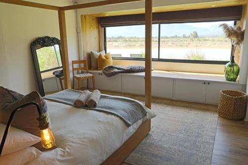 a bedroom with a bed and a large window at The Riverstone House in Romansrivier