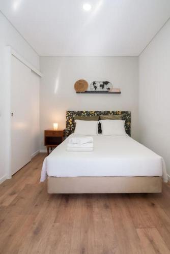 a bedroom with a white bed and a wooden floor at Oporto Seaside Village - Casa Savana in Matosinhos