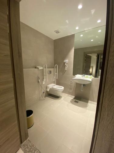 a bathroom with a toilet and a sink at Golden Tulip Amman in Amman