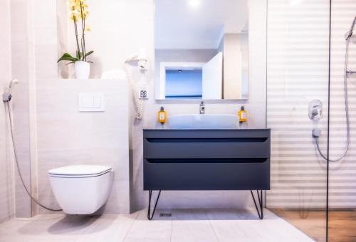 a bathroom with a sink and a toilet and a shower at Apeiro City Avant-garde Hotel in Sarajevo