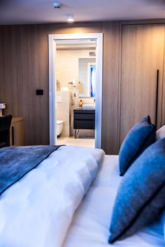 a bedroom with a bed with blue pillows and a bathroom at Apeiro City Avant-garde Hotel in Sarajevo