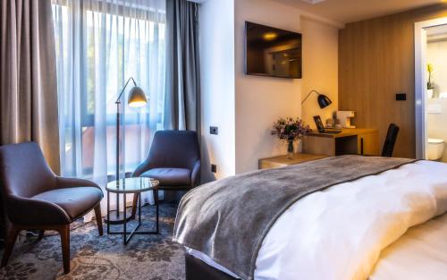 a hotel room with a bed and two chairs at Apeiro City Avant-garde Hotel in Sarajevo