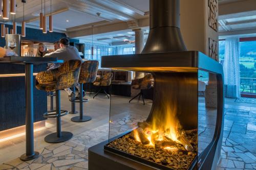 a fireplace in a restaurant with people sitting at a bar at AllgäuHotel Tanneck in Fischen