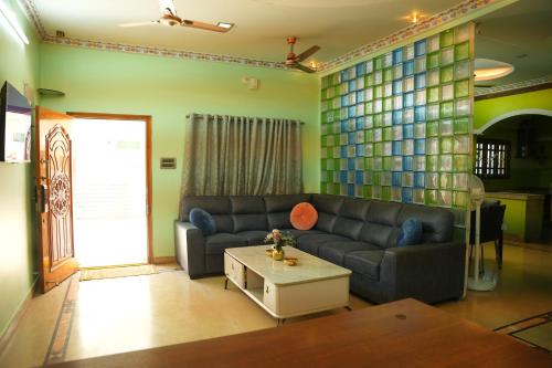 a living room with a couch and a table at The HR STAY INN TIRUPATI - LUXURY HOMESTAY - NEAR ALIPIRI BUS STAND AND KAPILATEERTHAM - 24 HRS HOT WATER-150 MBPS SPEED FREE WIFI & ALL OTT APPS in Tirupati