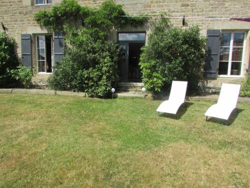 dwa białe krzesła siedzące w trawie przed domem w obiekcie Hauts De La Brancherie w mieście Léhon