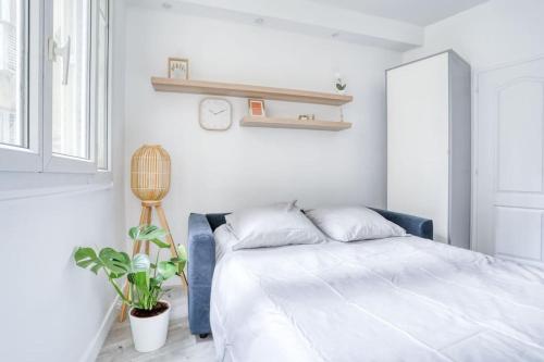 - une chambre blanche avec un lit et une plante dans l'établissement Le studio duret 1, à Paris