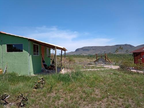 a green building in a field with mountains in the background at CÉU DE AGARTHA Retiros e Vivências in Alto Paraíso de Goiás