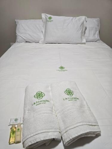 a bed with white sheets and towels on it at Confortável como a sua casa! in Ariquemes