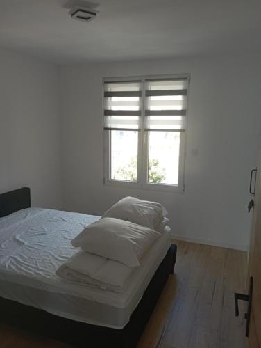 une chambre blanche avec un lit et une fenêtre dans l'établissement Lueurs des marées, à Merlimont