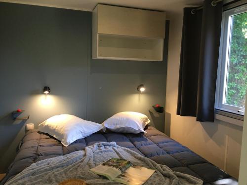 a bedroom with a bed with two pillows and a window at Flower Camping de Rouffiac in Angoisse