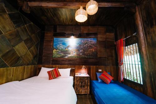 a bedroom with a bed and a painting on the wall at Ha Giang Xanh Retreat - Trekking, Tour, Motorbike Rental in Ha Giang