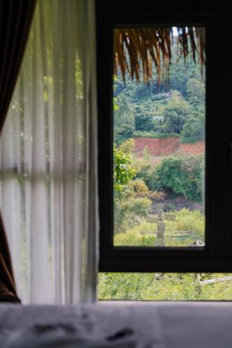a window with a view of a garden seen through it at Ha Giang Xanh Retreat - Trekking, Tour, Motorbike Rental in Ha Giang