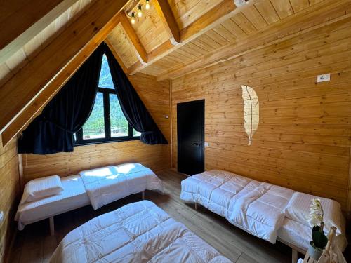 a bedroom with two beds in a wooden cabin at Thethi Villas in Theth