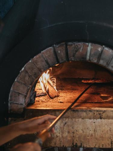 a person holding a stick in a brick oven at Alpina Alpendorf in Sankt Johann im Pongau
