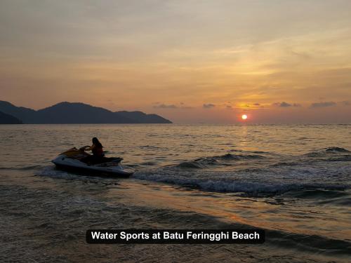 a person riding a boat in the water at the beach at By the Sea- Pool and Sea View in Batu Ferringhi