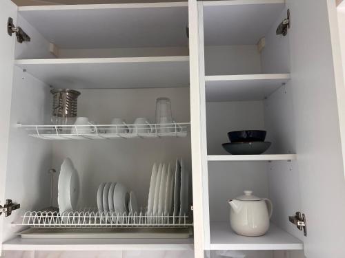 a white pantry with plates and bowls on shelves at 1912 Bed & Breakfast in Klaipėda