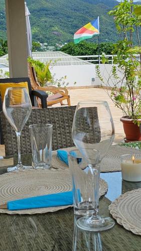 a table with three wine glasses on top of it at Harmony Self-Catering Apartments in Beau Vallon
