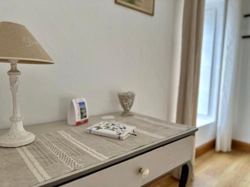 a table with a lamp and a book on it at Le Clos Beldane in Le Tâtre