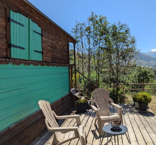 two chairs and a table on the deck of a cabin at Roulotte du Mas Rondole in Saillagouse