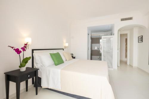 a white bedroom with a white bed and a black table at Casa Giuliani Capri in Capri