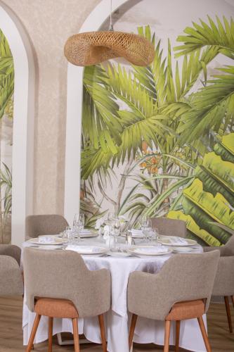 a dining room with a table with chairs and a palm mural at Lixus Beach Resort - All In in Larache