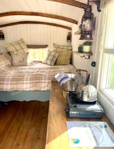 a small bedroom with a bed and a stove at The Little Green Shepherds Hut in Charlwood
