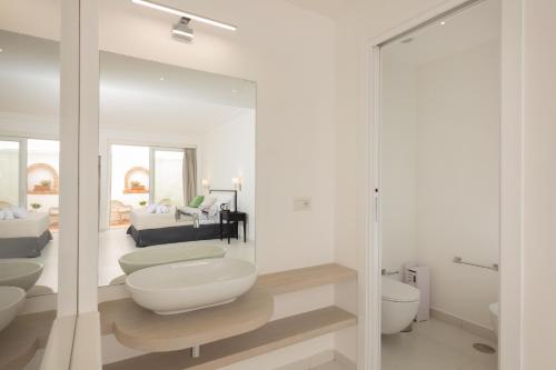 a white bathroom with two toilets and a living room at Casa Giuliani Capri in Capri