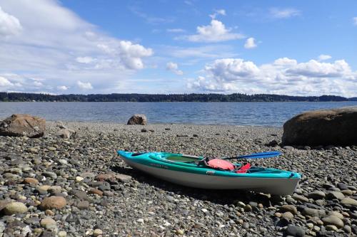 a boat sitting on a rocky beach next to the water at Puget Sound Orca Retreat in Poulsbo