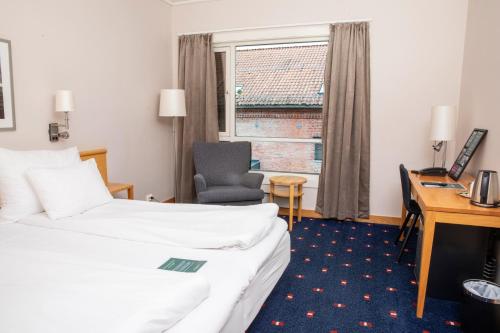 a hotel room with a bed and a desk and a chair at Home Hotel Bryggeparken in Skien