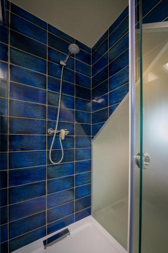 a bathroom with a shower with blue tiles at Bográcsozó Vendégház in Békésszentandrás