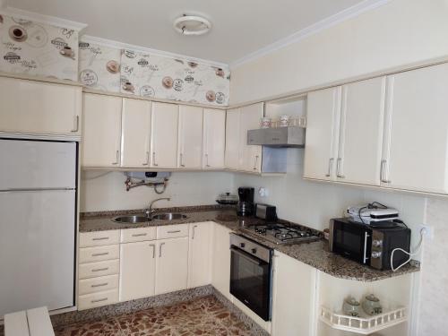 a kitchen with white cabinets and a sink and a microwave at Apartamento's Montiño in O Grove