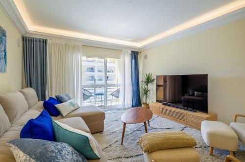 a living room with a couch and a tv at Portugal Portfolio - Parede Beach Apartment in Parede
