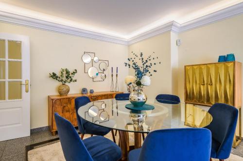 a dining room with a glass table and blue chairs at Portugal Portfolio - Parede Beach Apartment in Parede