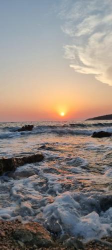 a sunset over the ocean with rocks in the water at Summer Park Residence Peljesac in Orebić