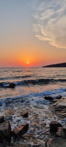 a sunset over the ocean with rocks on the beach at Summer Park Residence Peljesac in Orebić