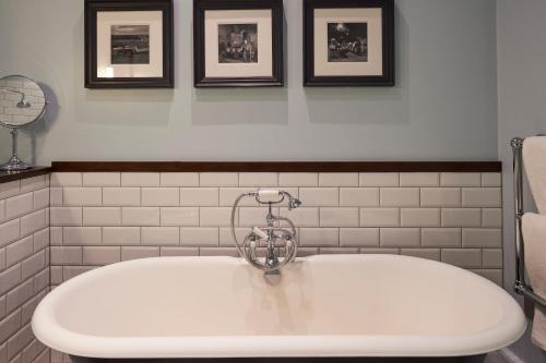 a white tub in a bathroom with pictures on the wall at Hotel Du Vin Edinburgh in Edinburgh