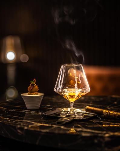 a glass of wine sitting on a table with a candle at Apeiro City Avant-garde Hotel in Sarajevo