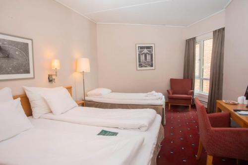 a hotel room with two beds and a chair at Home Hotel Bryggeparken in Skien
