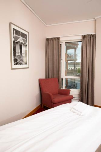 a bedroom with a red chair and a window at Home Hotel Bryggeparken in Skien